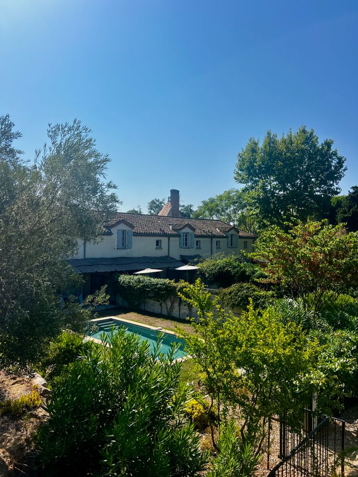 Idyllic villa with lush garden and pool under clear blue sky, a perfect summer retreat.